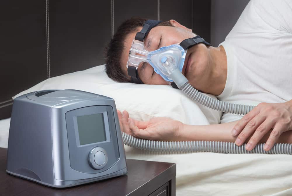 man sleeping with a sleep apnea machine on his face