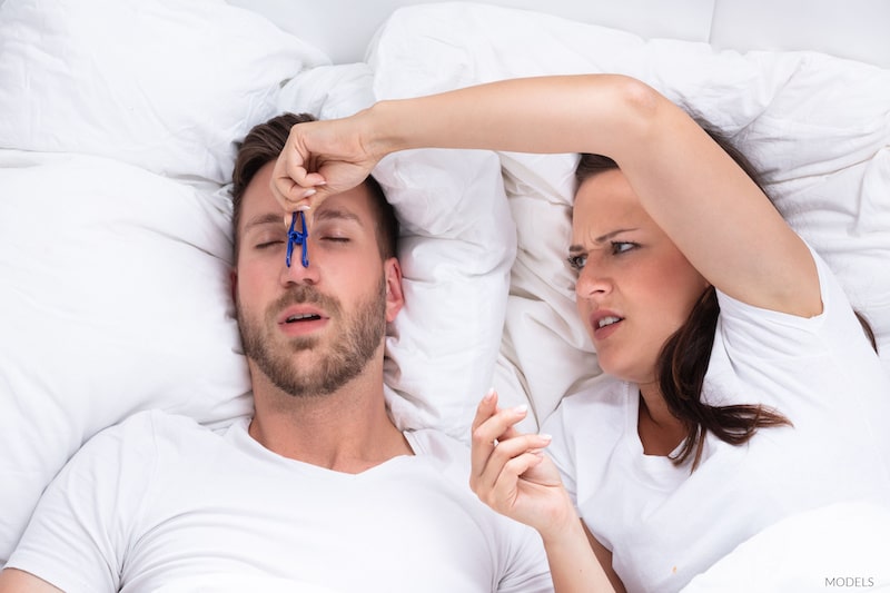 Woman plugging snoring partner's nose